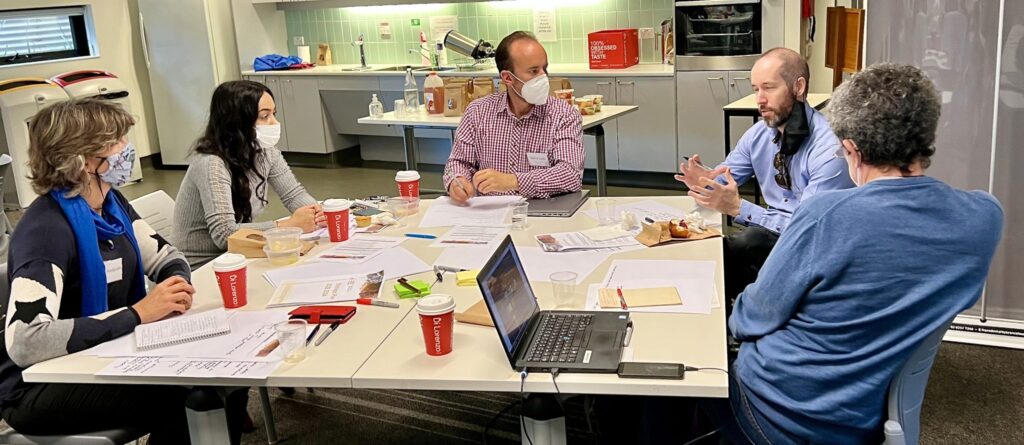 Five people sit around a table for a Niche Thinking professional development workshop with notes and laptops.